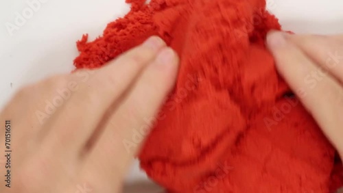 Human hands are pressing crumbly, malleable kinetic red sand. Asmr. A relaxing