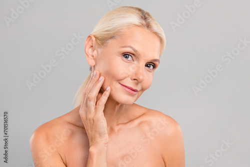 Portrait of attractive healthy smiling woman touching smooth delicate skin cleansing gel cream lotion isolated on gray color background photo