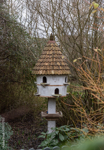 A dovecote shelter for birds and doves pigeons with multiple entrances and a pointed roof on a wooden post. Nesting sites man made by people to decorate and adorn gardens. Bird House, Handmade wooden, © num