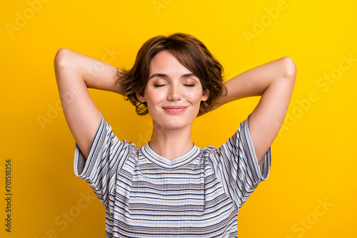 Photo of lovely dreamy girl dressed stylish clothes hold hands behind head enjoy vacation isolated on yellow color background