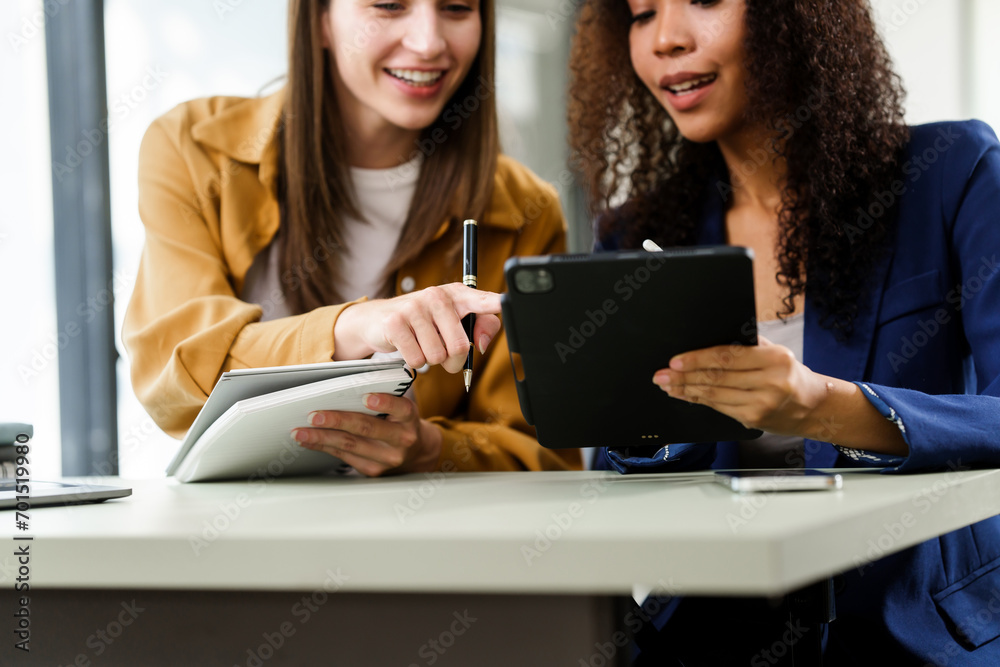 Caucasian and an African American university woman working together on a project, using a laptop and talking on a phone. Caucasian and an African American university woman working together on a project, using a laptop and talking on a phone.