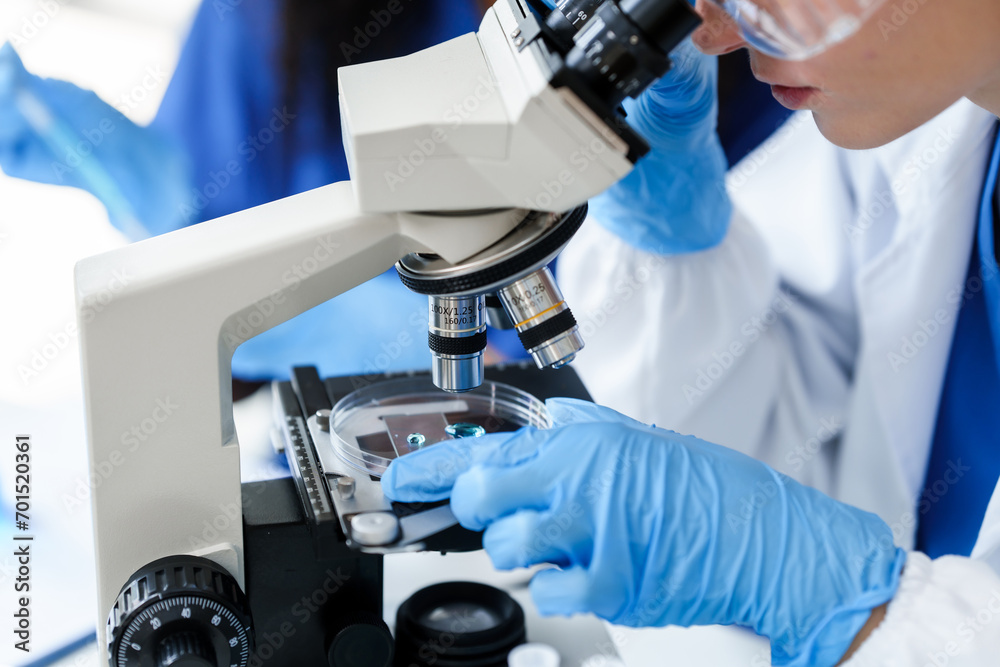 African American and a Caucasian researcher conducting a blood lab test, examining samples with a microscope in a medical laboratory. African American and a Caucasian researcher conducting a blood lab test, examining samples with a microscope in a medical laboratory.