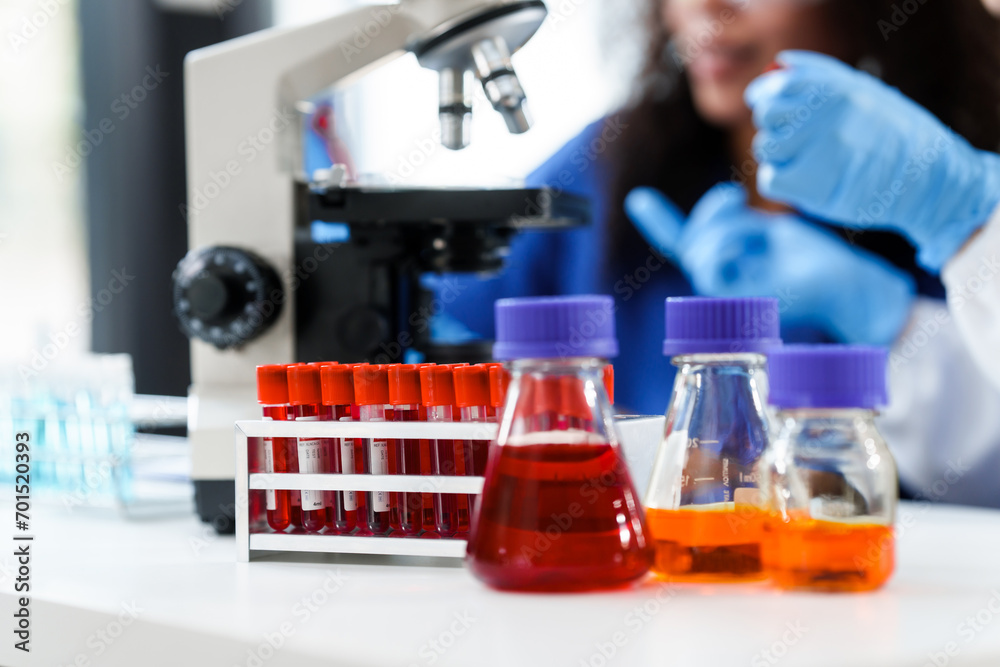 African American and a Caucasian researcher conducting a blood lab test, examining samples with a microscope in a medical laboratory. African American and a Caucasian researcher conducting a blood lab test, examining samples with a microscope in a medical laboratory.