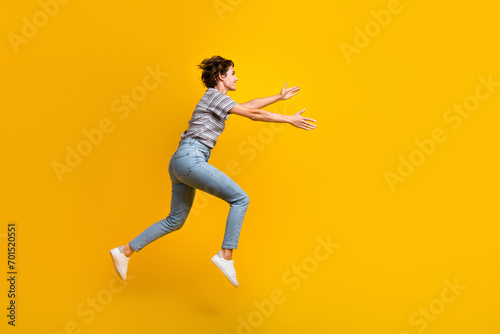 Full size profile photo of sportive energetic girl jump run arms catch empty space isolated on yellow color background © deagreez
