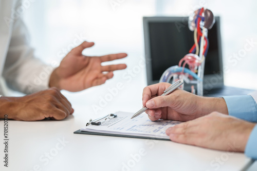 close-up of male patient consultation with doctor, explaining model of reproductive system, possibly discussing prostate cancer, cystitis, or urinary tract infection.