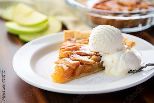 A delicious piece of apple pie served with a scoop of vanilla ice cream.  photo