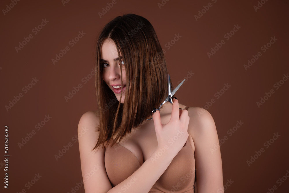 Obraz premium Haircut. Portrait of young woman hairdresser cutting hair with scissors. Girl with beautiful hair look at scissors. Haircut hairstyle with bangs. Hair care. Girl with straight hair holds scissors.