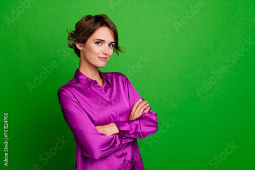 Photo of half turned lovely successful person crossed hands empty space ad isolated on green color background photo