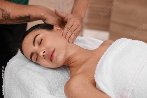 Woman receiving professional neck massage on couch indoors