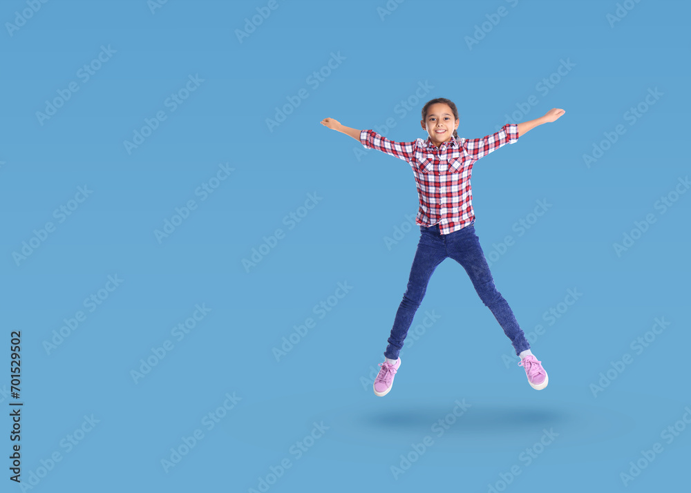 Cute girl jumping on light blue background, space for text