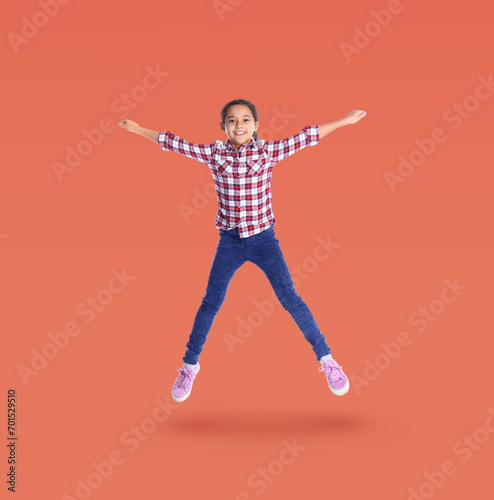 Happy cute girl jumping on coral background