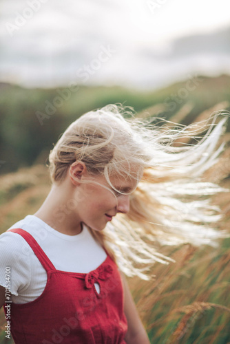 profile portrait of a  girl with long blond hair in a field of wheat