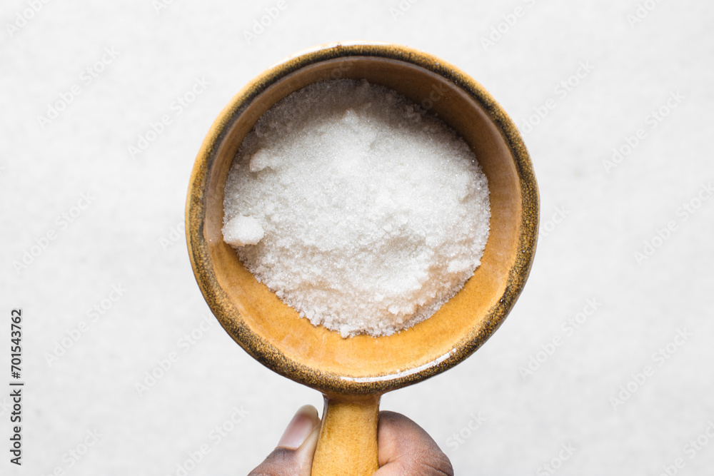 A bowl of white sugar, top view of granulated sugar in a brown bowl A bowl of white sugar, top view of granulated sugar in a brown bowl