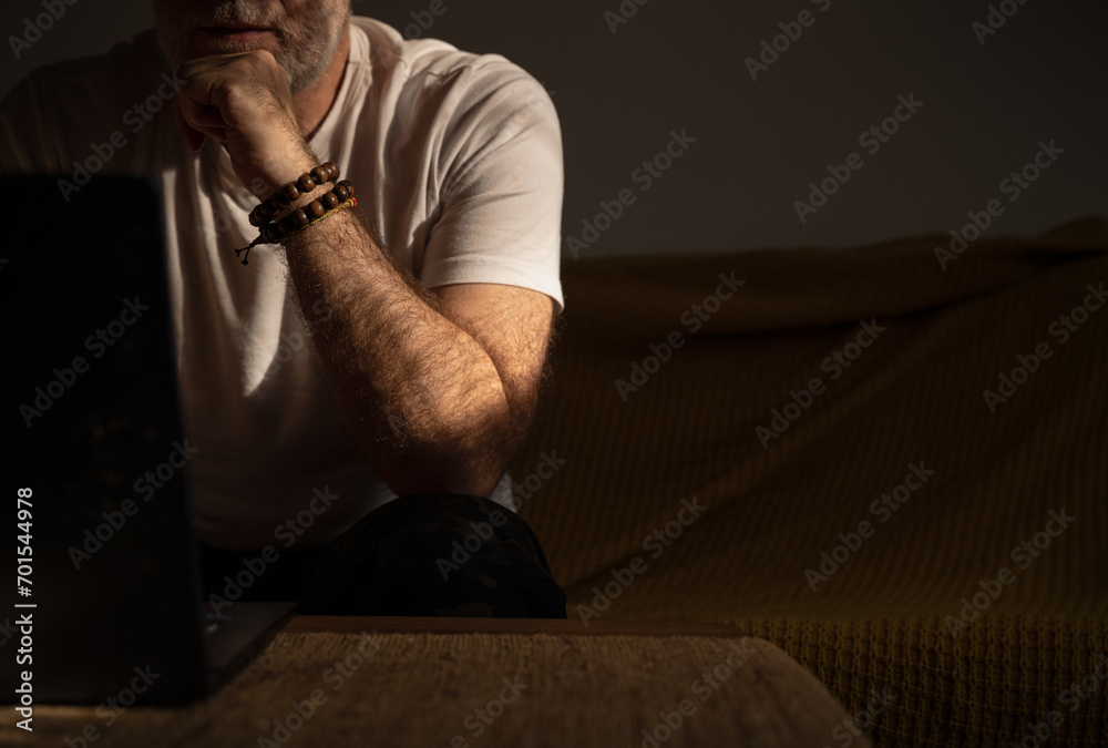 Closeup of arm of adult man using laptop with bracelets on wrist