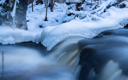 Blue hour by natural stream in the forest in Finland in winter © Milla Rasila