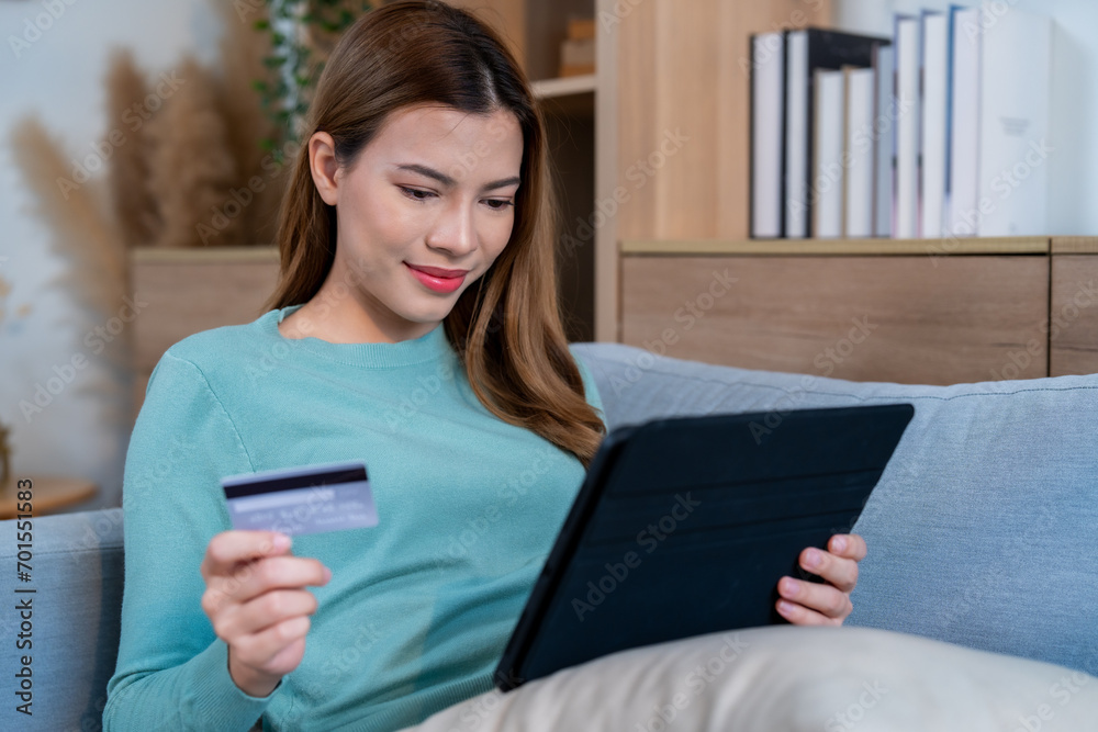 Fototapeta premium A woman express on her face with cheerful, conveying a sense of satisfaction and happiness with her online shopping and successful credit card transactions.