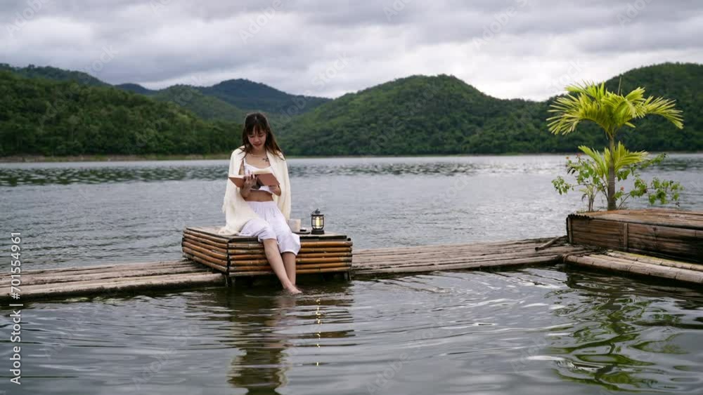4K Happy Asian woman relax and enjoy outdoor lifestyle travel nature forest mountain on summer holiday vacation. Attractive girl sitting on lake house balcony with reading a book and drinking coffee. 4K Happy Asian woman relax and enjoy outdoor lifestyle travel nature forest mountain on summer holiday vacation. Attractive girl sitting on lake house balcony with reading a book and drinking coffee.