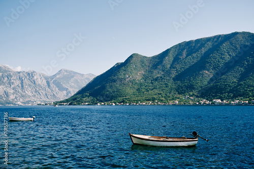 Fishing boats moored in the sea at a distance from each other against the backdrop of mountains