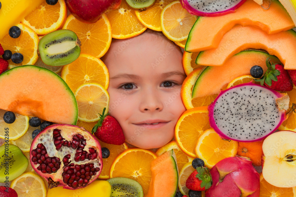 Healthy food background. Studio photo of different fruits with kids face. Mix of different fruits and berries. Cute little boy eats fruits. Kid eating vitamins. Close up kids face.