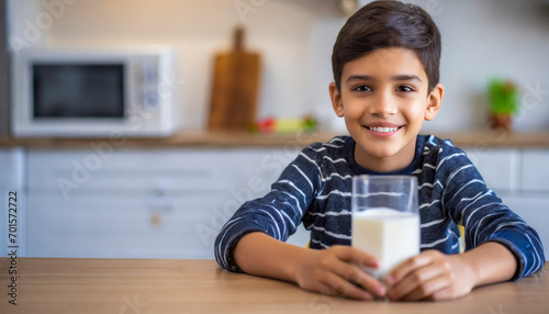 Portrait of smiling boy holding glass of milk in kitchen at home