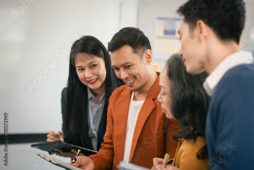 Asian business professionals team actively engaged in collaborative meeting in boardroom, sharing opinions and working together with visible happiness.