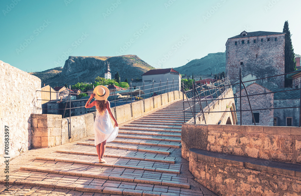 Female tourist with white dress on famous old bridge in Mostar city- Bosnia and herzegovina