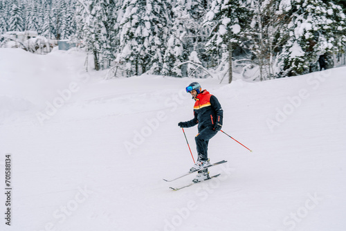 Man in a ski suit is skiing with his leg bent at the knee on the slope of a snowy mountain