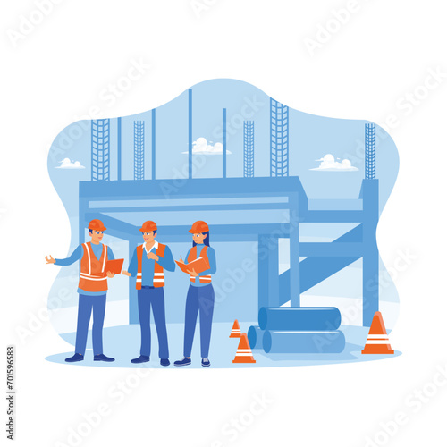 Young architects and engineers in vests and safety helmets on a building site. Discuss the draft development plan using a laptop and notebook. Building construction sites concept. 