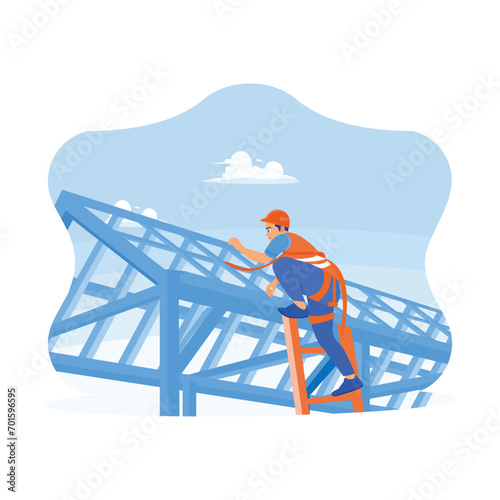 Construction workers wear safety harnesses when working on roof structures on construction sites. Roofer using a pneumatic nail gun, installing roof tiles. 