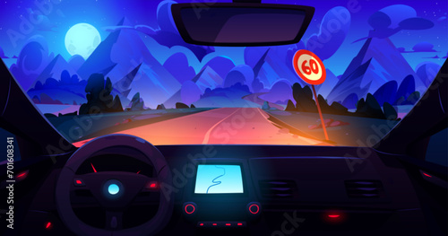 View from car through windshield on road with sign going across meadow to high rocky mountains at night under moon light. Dark dusk landscape with hills through automobile window with navigation panel