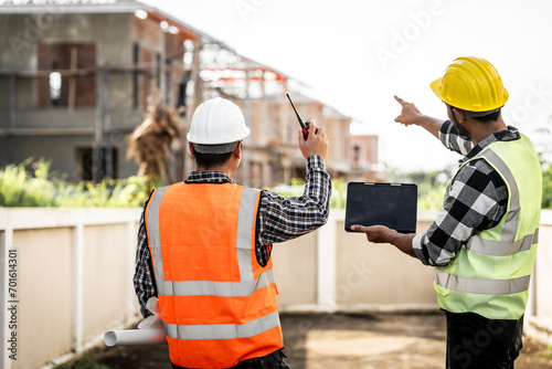 Asian people, two man, holding blueprints Structural engineers examine structural plans for office buildings and housing developments on-site, discussing work at construction site. photo