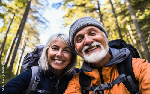 Smiling senior couple taking selfie while hiking in the woods with backpacks 