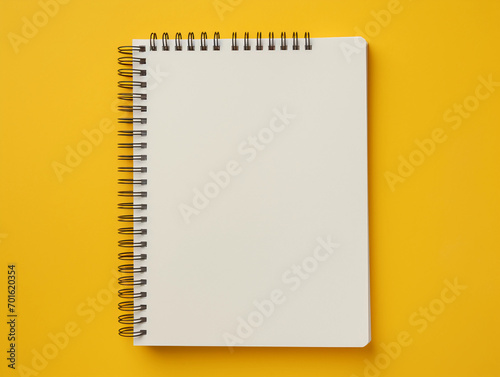 Blank spiral notebook over yellow background flat lay 