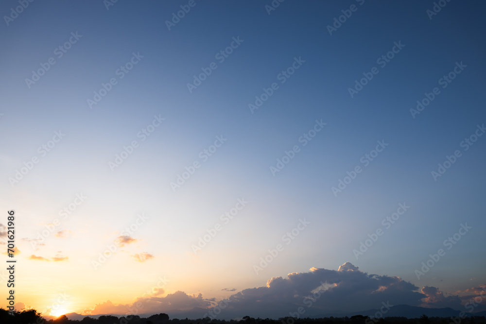 Fototapeta premium Beautiful sky and cloud at high. Include space, light of nature, sunset, sunrise. Colorful with yellow, orange and blue color at evening time in autumn for scene, backdrop, background and wallpaper.