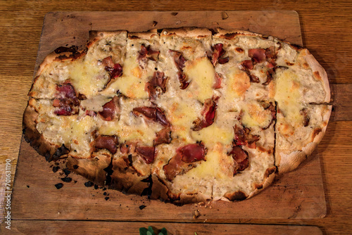 Flammekueche or tarte flambee with fromage blanc cheese and cured ham at a traditional winstub restaurant in Strasbourg, Alsace, France photo