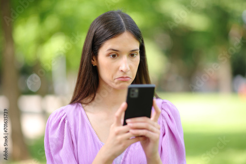 Perplexed woman checking strange news on phone