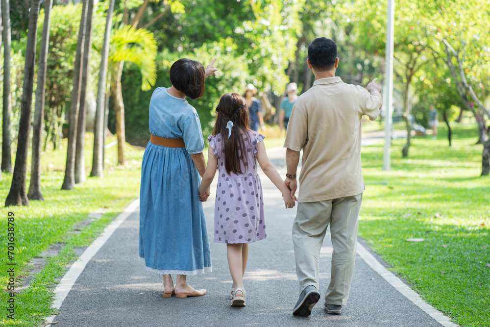 Happy Asian family holding hands and walking, enjoying leisure time with outdoor activities in a public park. Happy Asian family holding hands and walking, enjoying leisure time with outdoor activities in a public park.