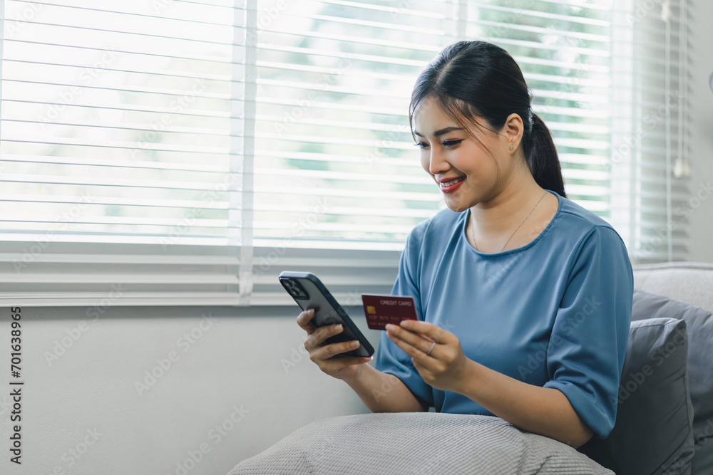 Happy young asian woman holding a credit card and using mobile phone. Businesswoman doing online shopping on smartphone at home. Happy young asian woman holding a credit card and using mobile phone. Businesswoman doing online shopping on smartphone at home.