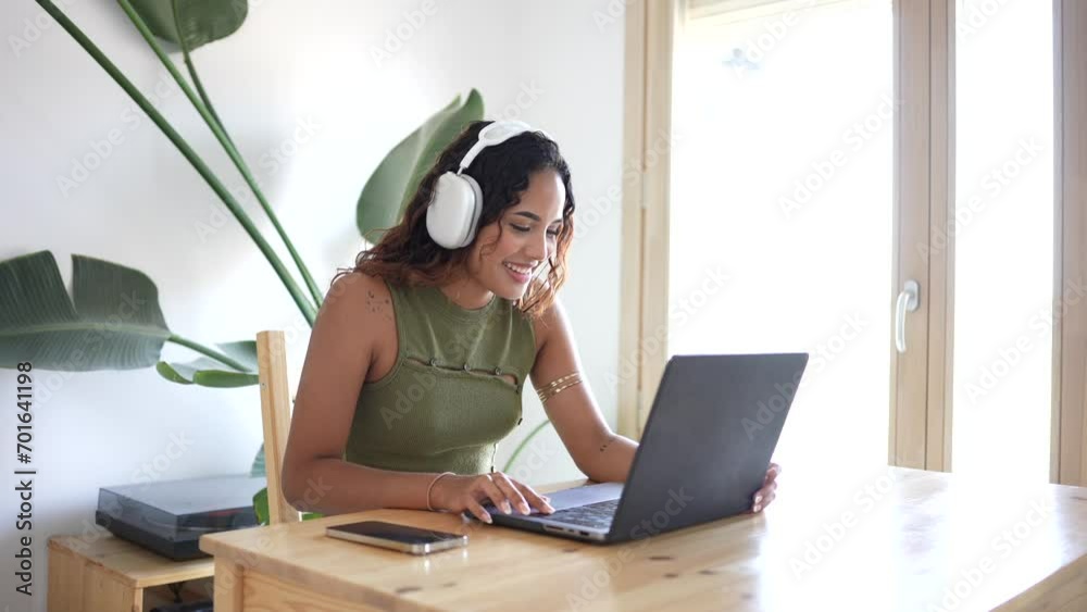 Happy woman working from home. In a wood-crafted haven, a girl immersed in work, laptop and headphones in a minimalist home with a touch of green. Focus and nature's serenity. Minimalist work space. Happy woman working from home. In a wood-crafted haven, a girl immersed in work, laptop and headphones in a minimalist home with a touch of green. Focus and nature's serenity. Minimalist work space.