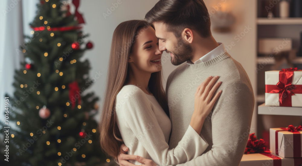 Lovely young couple hugging at home holding gift box, happy giving concept.