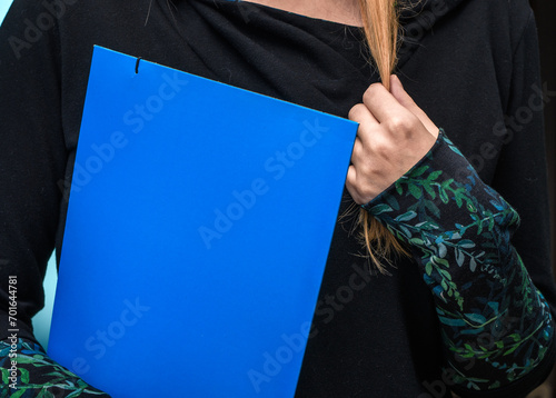 Zawstydzona kobieta trzyma się za włosy podczas formalnej rozmowy z dokumentami w dłoni 