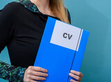 Dziewczyna trzyma w rękach teczkę z napisem CV, rozmowa kwalifikacyjna