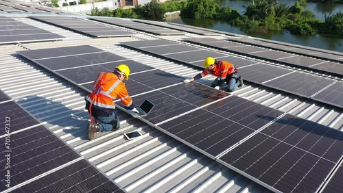 Engineering technician is professional trained in skills and techniques installing solar photovoltaic panels system on power industrial factory roof, Engineering concepts to good environment. photo