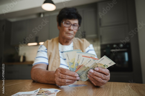 Senior woman counting currency at home photo
