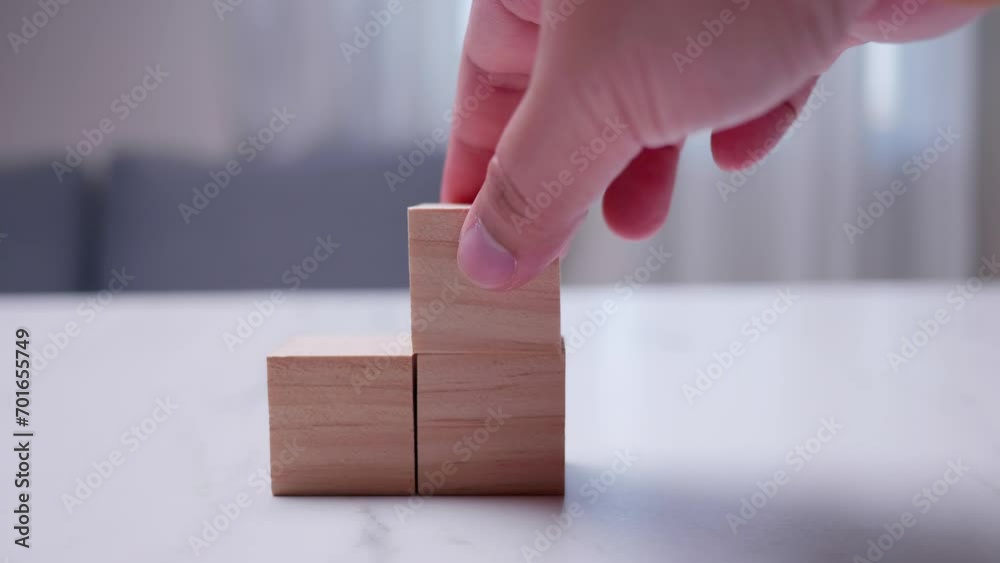 Taking a close-up shot of an individual stacking wooden blocks on top of each other on a table.