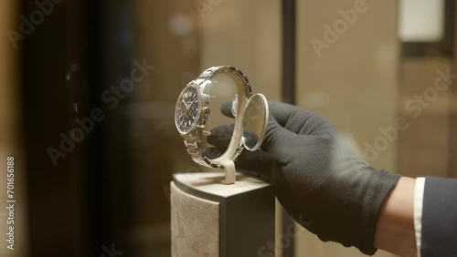 Gloved boutique retailer hands removing luxury wristwatch from store window display photo