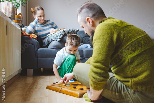Father playing checkers with son on floor at home photo