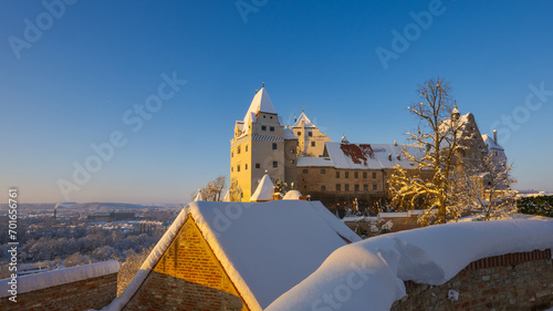 The outside of Castle Trausnitz in Landshut, Lower Bavaria with snow covered walls and roofs in winter on sunny day photo