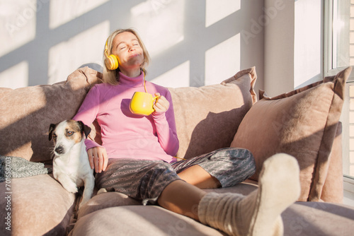 Smiling adult woman with closed eyes in headphones photo