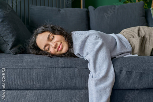 Smiling woman lying down on sofa with eyes closed at home photo